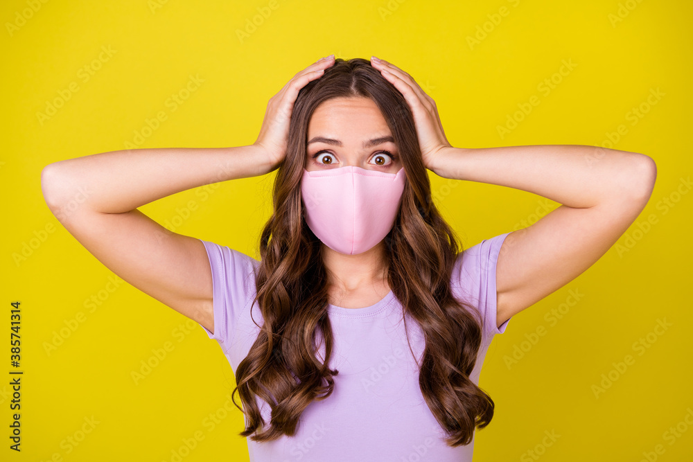 Close-up portrait of attractive scared worried wavy-haired girl wearing safety mask omg isolated over bright yellow color background