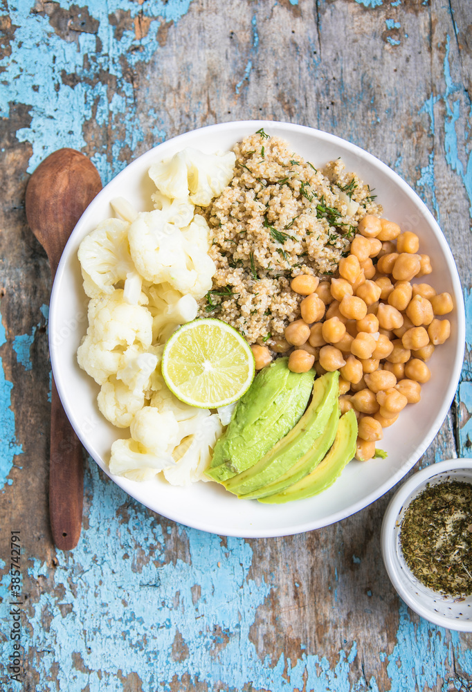 A bowl of healthy vegan and vegetarian lunch or dinner. Salad of fried chickpeas, quinoa, avocado, cauliflower on a light background.Top view, flat lay A bowl of healthy vegan and vegetarian lunch or dinner. Salad of fried chickpeas, quinoa, avocado, cauliflower on a light background.Top view, flat lay