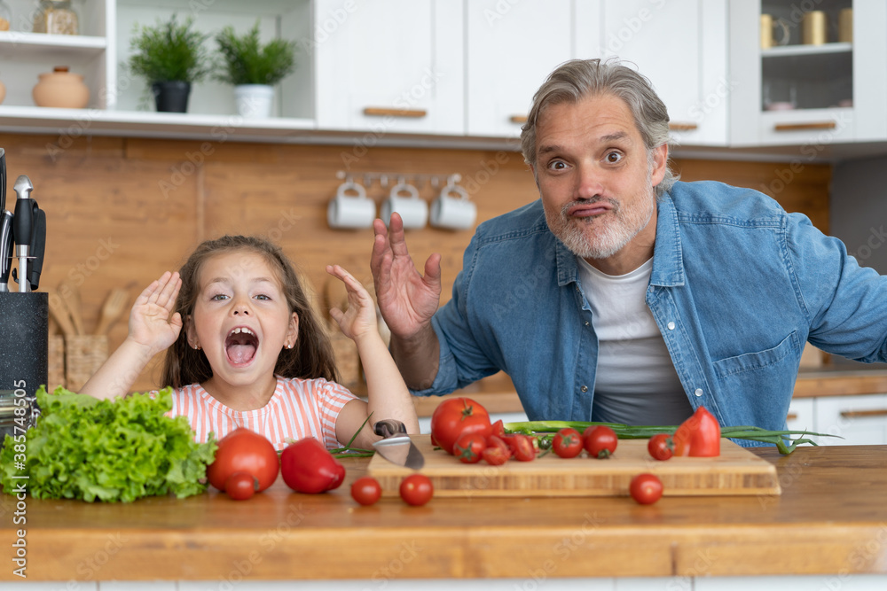 Cute little girl and her handsome dad are having fun while cooking in kitchen at home Cute little girl and her handsome dad are having fun while cooking in kitchen at home