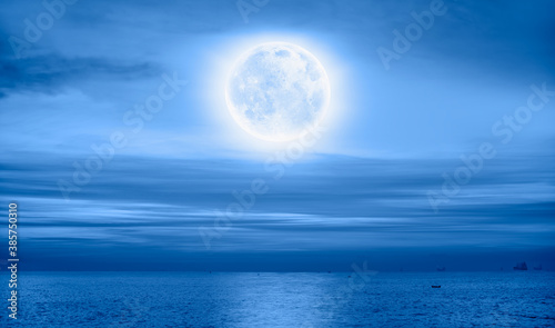 Night sky with moon in the clouds on the foreground blue sea  Elements of this image furnished by NASA