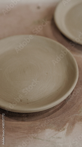 Ceramic tableware for the home. Bowls, cups, spoons, molds, ceramic plates on the background of the house and flowers.