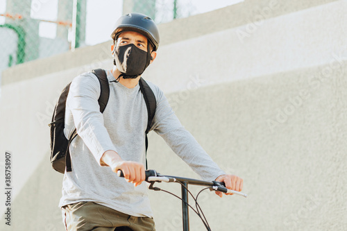 Cyclist man wearing face mask in the city. Concept of bicycles as a safer form of transportation during the New Normal