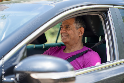 Elderly man driving car. A middle eastern dark skin senior retired man driving a car, portrait from the side.