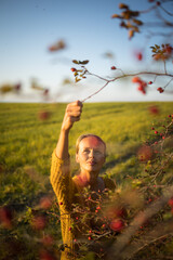 Pretty, young woman collecting rosehip fruit in autumn nature
