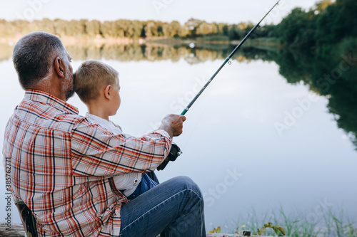 boy with his grandfather fishing on lake