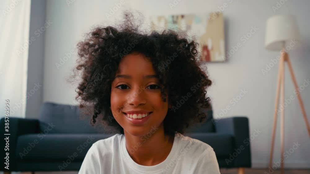 Selective focus of smiling african american girl looking at camera at home Selective focus of smiling african american girl looking at camera at home