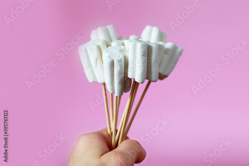 bouquet of marshmallows on pink background. a hand holding a bouquet of sweets