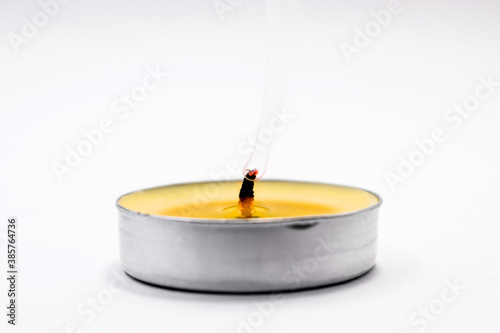 on a light background in the center there is a yellow extinguished candle from the wick smoke rises up photo