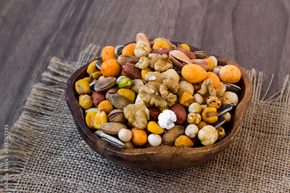 Mixed,crispy, dry nuts in a wooden plate on wooden table,with jute napkin Mixed,crispy, dry nuts in a wooden plate on wooden table,with jute napkin