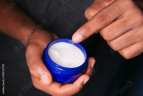  man applying beauty cream onto skin at home top view 