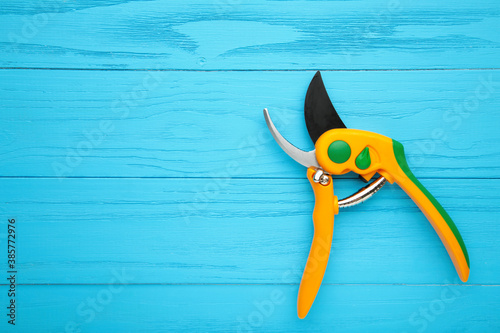 New yellow gardening secateurs on a blue wooden background.