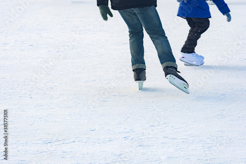 Teenagers go ice skating on the ice rink.