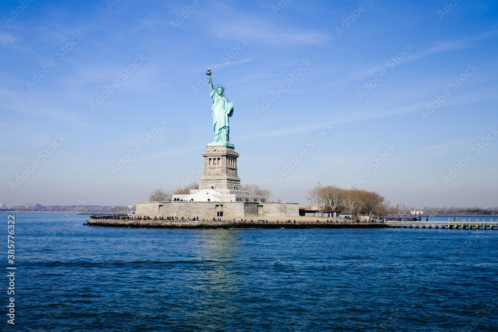 Statue of Liberty in NY Harbor on bright sunny day with blue sky