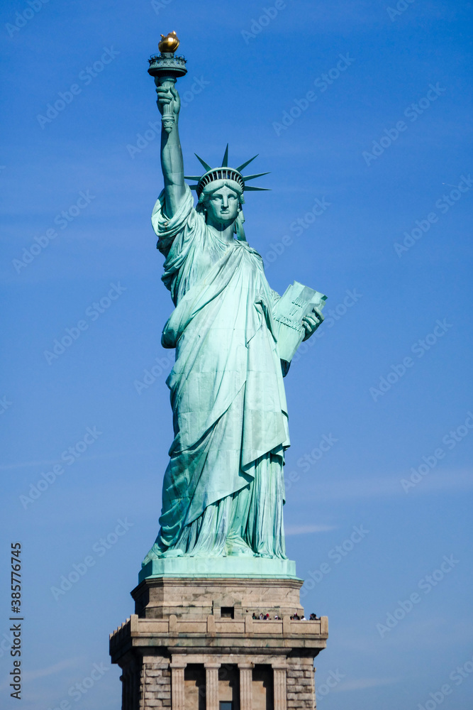 Fototapeta premium Statue of Liberty in NY Harbor on bright sunny day with blue sky