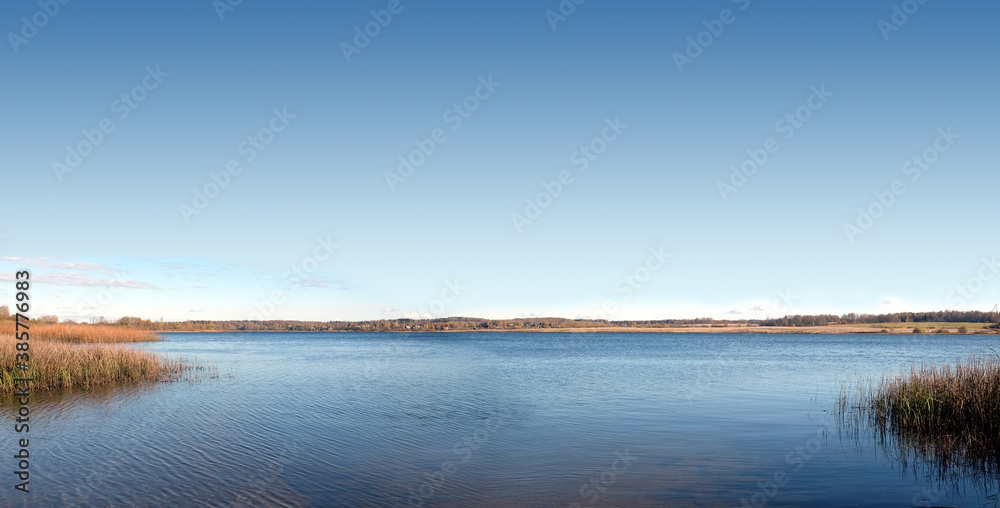 Quiet backwater on a rural lake with panoramic view of the village and forest far away on the horizon