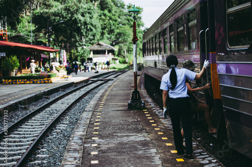 Woman officer of train take care of passenger for enter the train at train station at KhunTan railway station in Lamphun province.