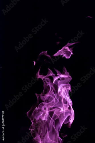 Close-up vertical picture of an isolated bright purple flame with numerous of tongues on the black background 