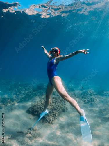 Happy freediver woman with New year cap glides underwater in blue sea. Christmas holidays concept