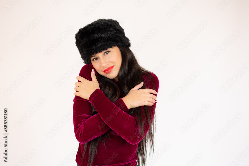 Portrait of a pretty young girl in red sweater hugging herself. Concept of selfish emotion.