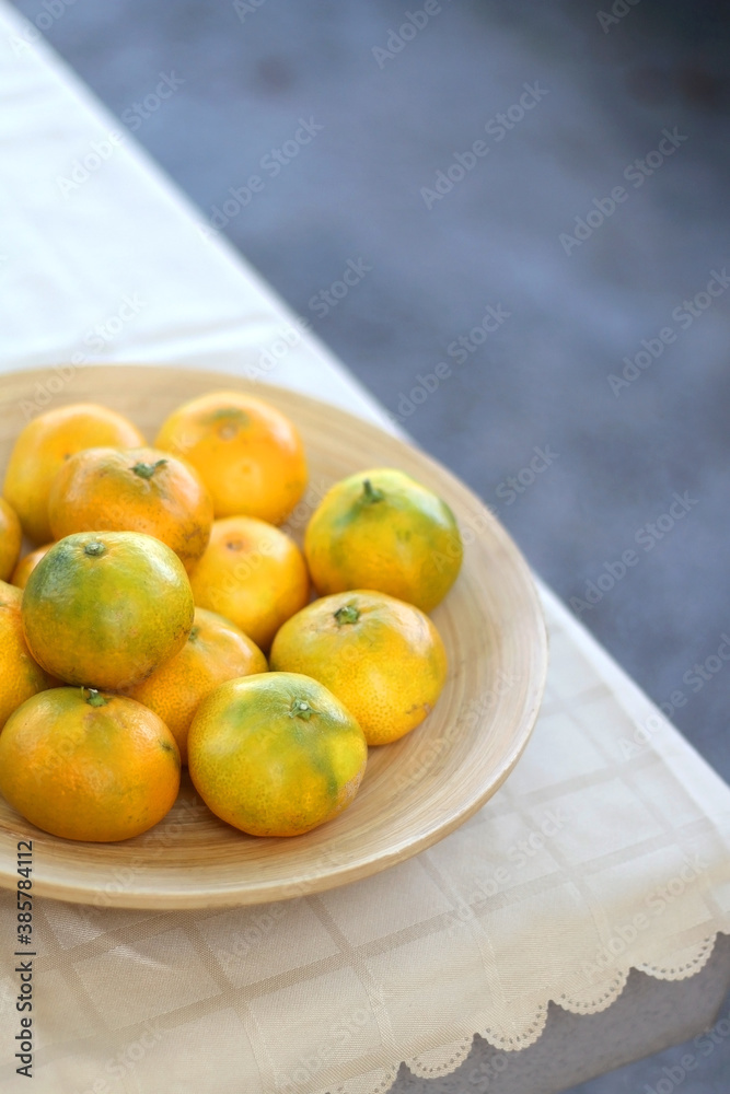 Wooden bowl full of tangerines on a table. Selective focus.