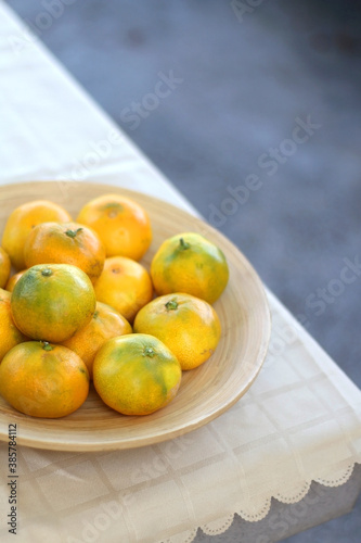 Wooden bowl full of tangerines on a table. Selective focus.