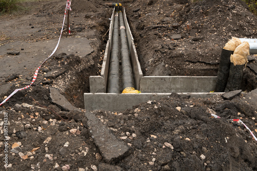 Repair of sewer pipes, water supply or drainage system. Underground to operate the equipment. Thick water pipes lie in a concrete box in a dug hole in the ground, preparing for the heating season photo