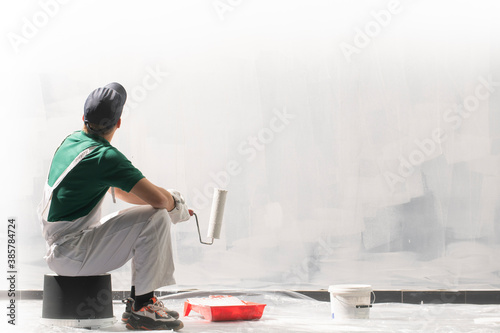 Fotografie Male decorator painting a wall with white color