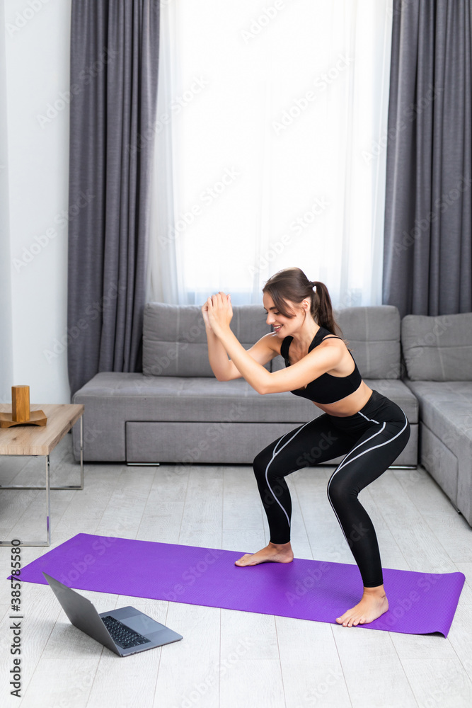 Attractive young woman in sportswear doing sit-ups in living room, training legs, trying to form perfect butt shape, squatting at home. Attractive young woman in sportswear doing sit-ups in living room, training legs, trying to form perfect butt shape, squatting at home.
