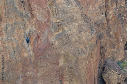 Solo rock climber taking a break on the smallest of ledges on the side of Smith Rock just north of Bend  Oregon