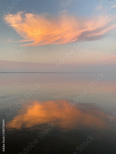 large orange sunset cloud reflecting onto bay water