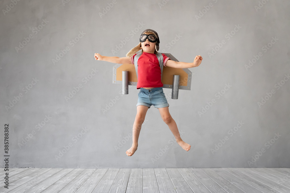 Child with jetpack jumping against grey concrete background