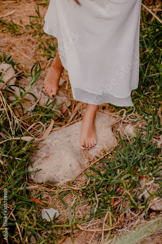 The girl's feet walk on the autumn grass.