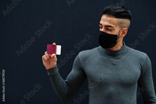 Middle eastern man in gray turtleneck and black face protect mask show Qatar flag isolated background. photo