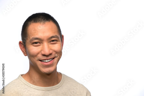Portrait of young man of Asian descent with smirk on white background  photo