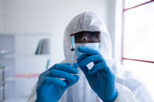 Health worker wearing protective clothes holding a syringe