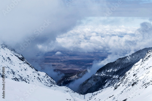 Carpathian mountains covered with snow (Balea lake area) and Fagaras county in the valley, Transfagarasan, Romania.