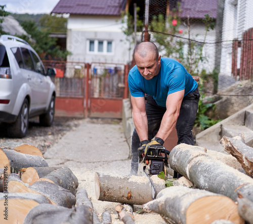 Farmer with chainsaw cutting wood