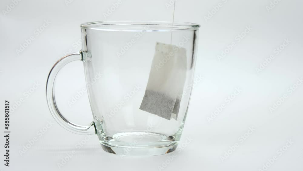 The tea bag is lowered into a transparent Cup. cooking chayana on a white background. The tea bag is lowered into a transparent Cup. cooking chayana on a white background.