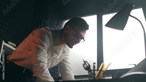 Low angle shot of successful smiling businessman, watching reading on laptop, feeling happy and satisfied with good results, celebrating victory at stock market, glad to receive promotion
