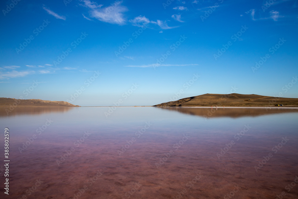 Pink salt lake Sasyk-Sivash, Yevpatoria, Crimea. The water of this lake is strongly saturated with salt and has a pink color. Very beautiful landscape with pink lake and blue sky with clouds.