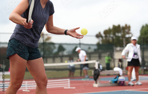 A woman serves during a pickleball tournament.