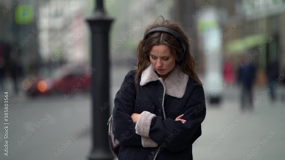 Cute girl is sad on a walk around the city goes and listens to music in wireless headphones Cute girl is sad on a walk around the city goes and listens to music in wireless headphones