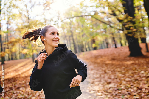 Young woman jogging in autumn forest photo