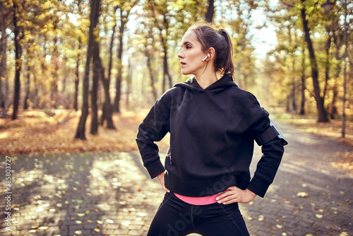 Young female jogger during break looking sideways in autumn forest