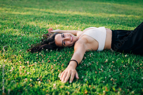 Smiling young woman relaxing on grass at public park photo
