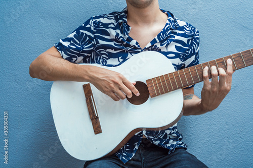 Musician playing guitar against blue wall