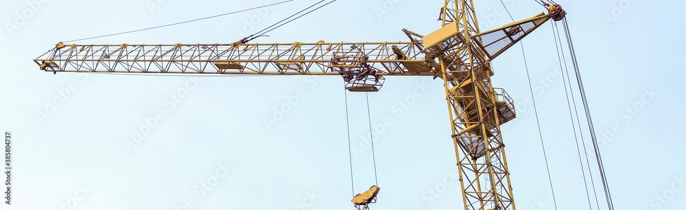 Construction crane stands on the background of the sky. Construction site. Tower crane. Banner.