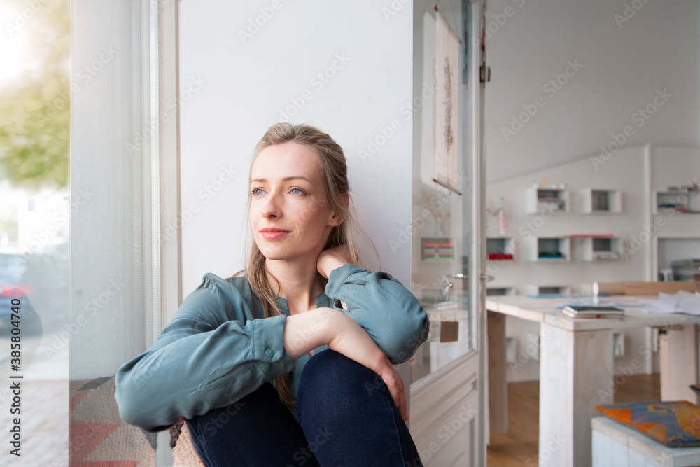 Relaxed woman having a break in home office looking out of window Relaxed woman having a break in home office looking out of window