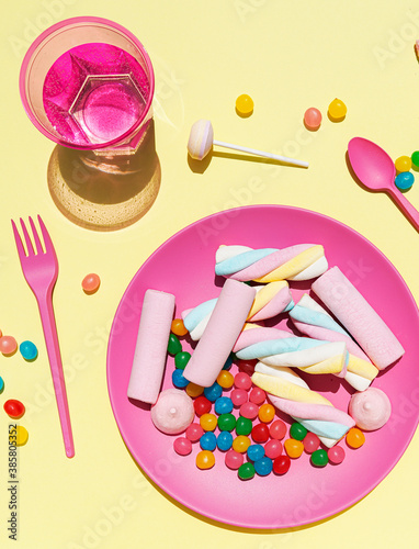 Studio shot of glass of water and plastic plate filled with various sweets