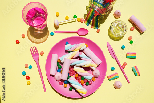 Studio shot of glass of water and plastic plate filled with various sweets